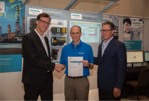 Dr. Hartmut Klocker of Karlsruhe Germany, Segment Lead Automation and Engineering Systems at Siemens (left) and Todd Gardner, Vice President of Siemens Process Industry and Drives, based in the USA (right), present Ken O’Malley, President of aeSolutions, the Siemens SIMATIC PCS 7 Process Safety Specialist certification.